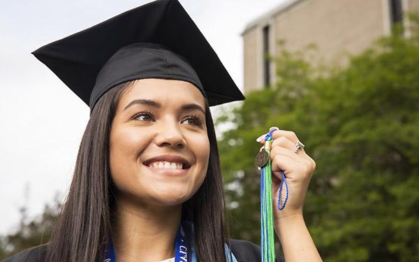 一位戴着学士帽和学士服的威斯康星大学毕业生举着流苏.